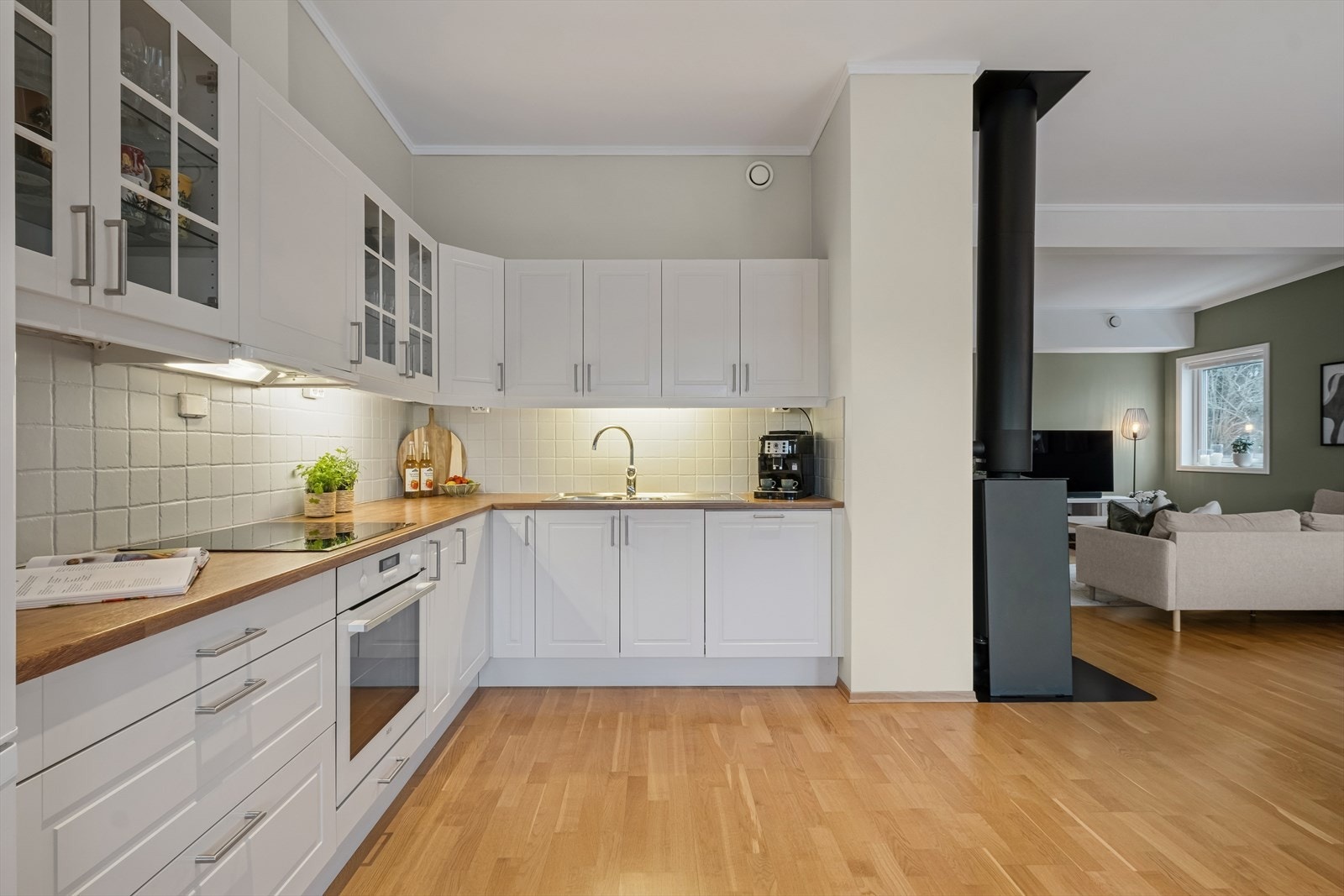 Kjøkkenet har en pen og tidløs Sigdal-innredning med hvite profilerte fronter og laminert benkeplate med nedfelt vaskekum. Galleribilde