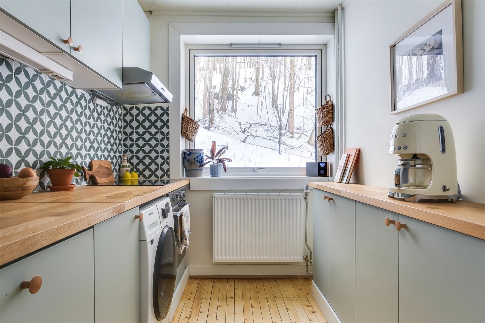 Kjøkkeninnredning med glatte fronter og laminert benkeplate, integrerte hvitevarer som oppvaskmaskin, platetopp, stekeovn samt frittståendekjøl/fryseskap. Galleribilde