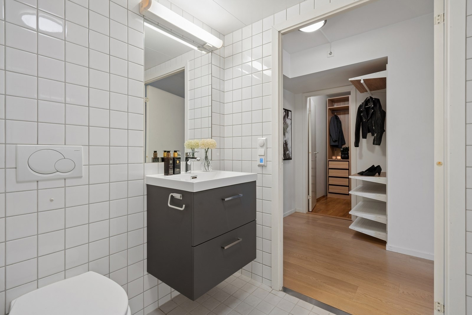 Badet har en pen innredning fra 2024 med glatte, mørke fronter og heldekkende servant. Over innredningen er det speil med belysning. Galleribilde