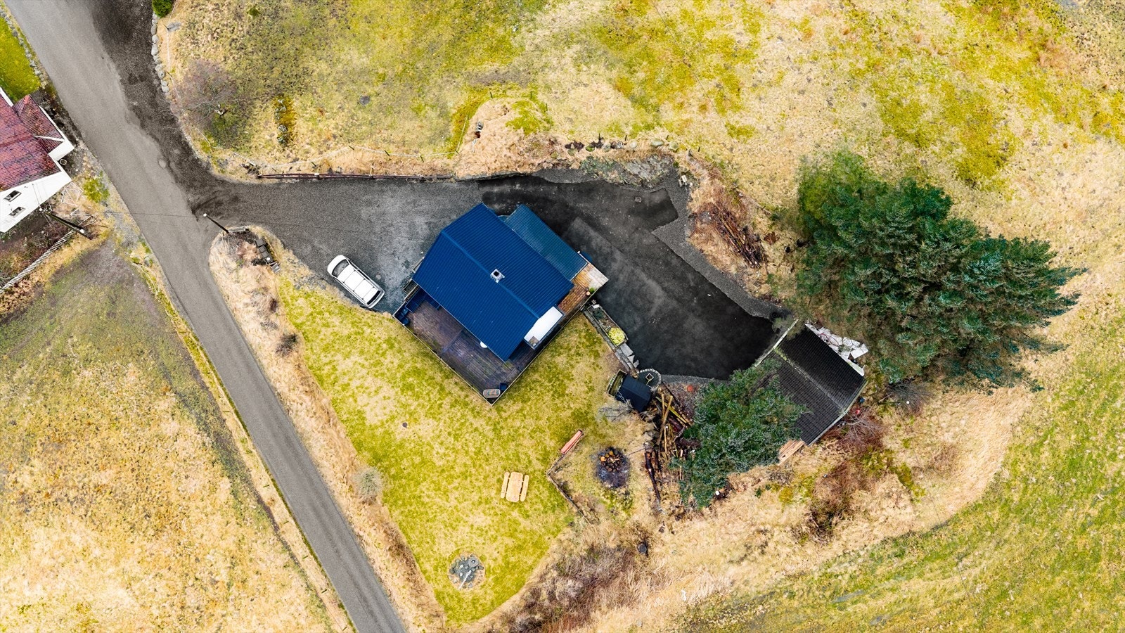 Tomten er opparbeidet med singlet innkjørsel, asfaltert gårdstun samt hage med plen og noe beplantning Galleribilde