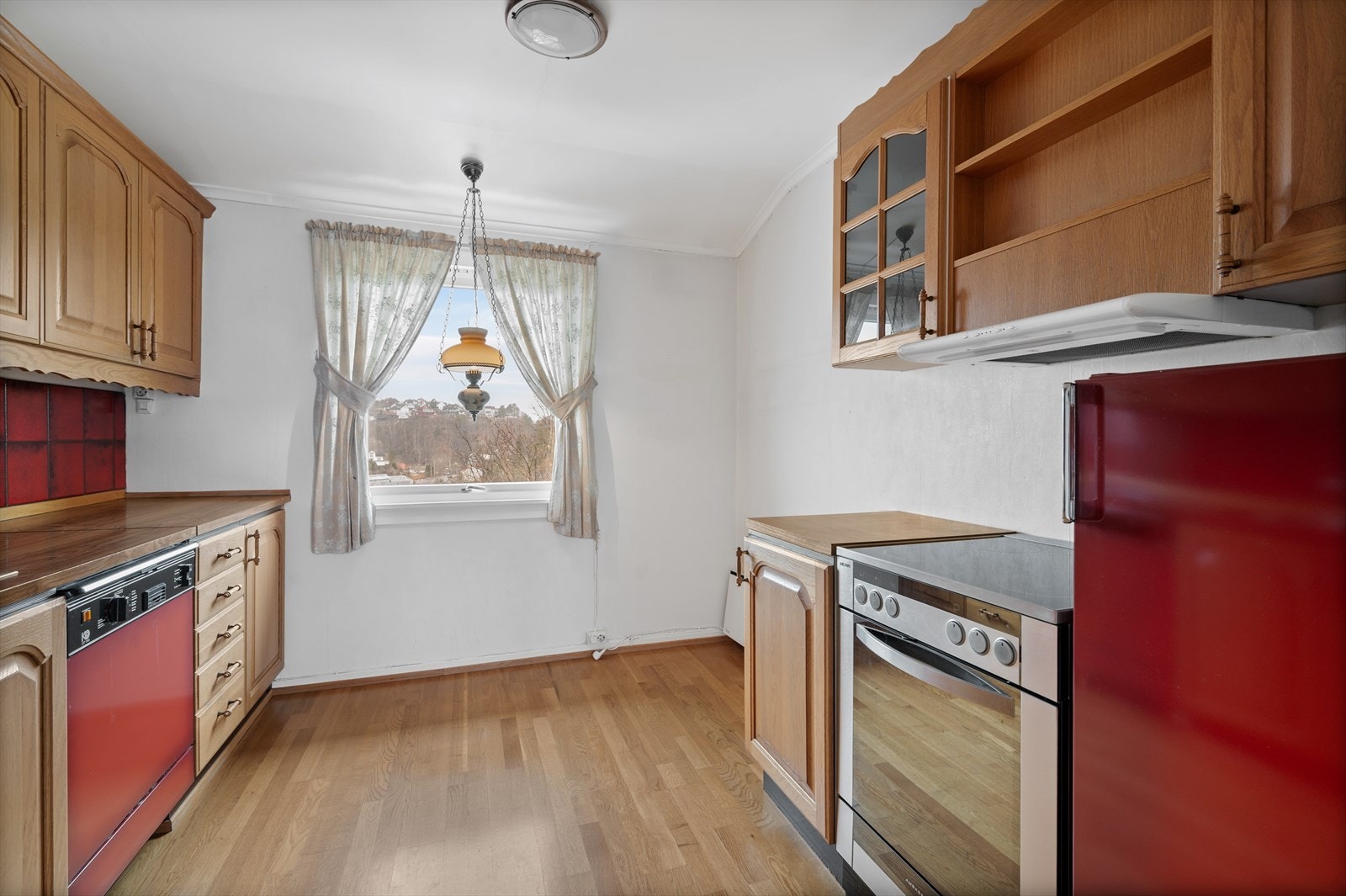 Kjøkkeninnredning med fronter av eik, ventilator, oppvaskmaskin og kjøleskap. Galleribilde