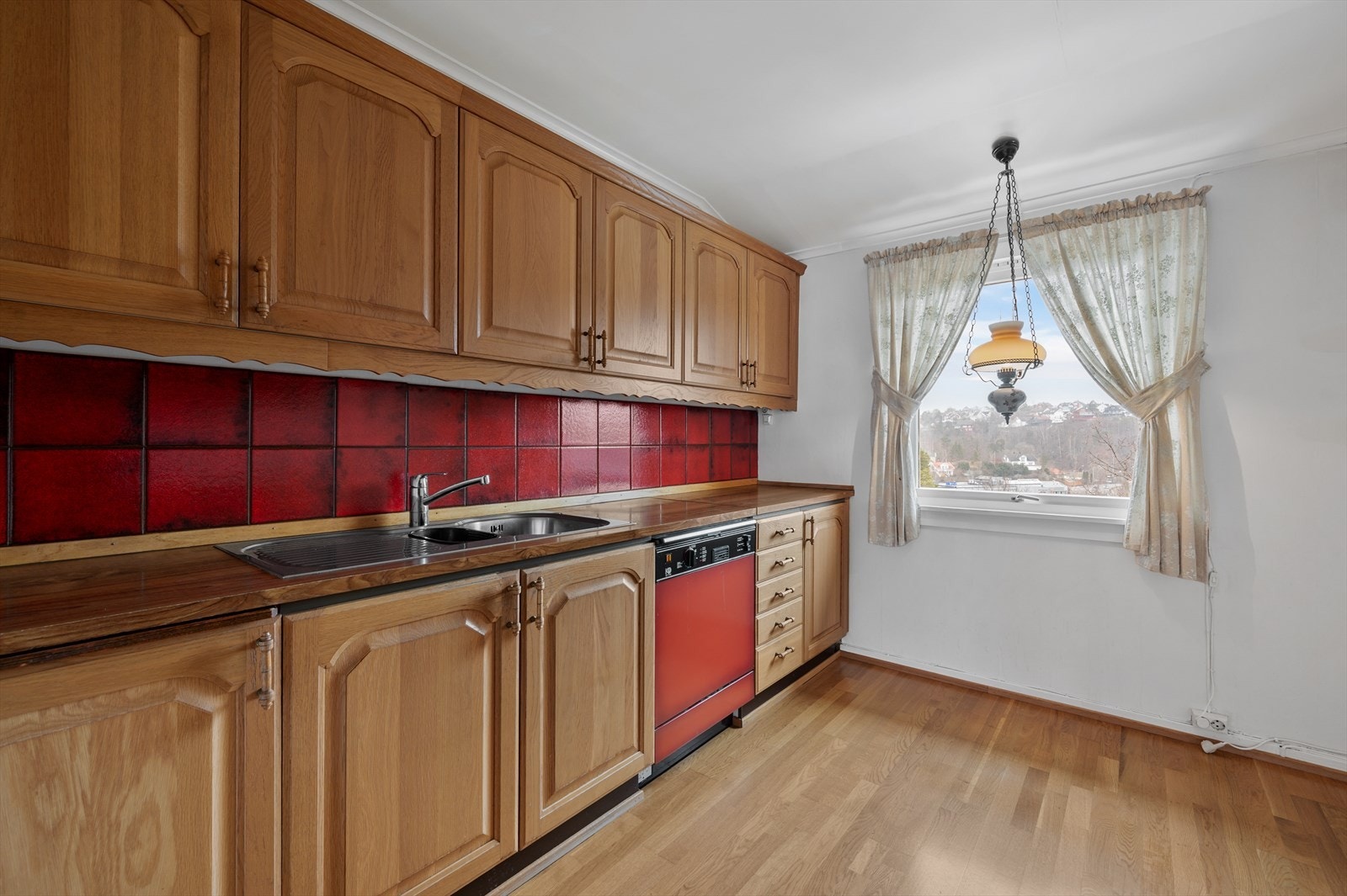 Kjøkkeninnredning med fronter av eik, ventilator, oppvaskmaskin og kjøleskap. Galleribilde