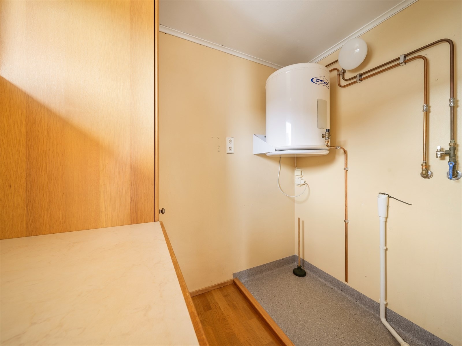 På enden av kjøkken bak en halv vegg er det opplegg for vaskemaskin. Galleribilde