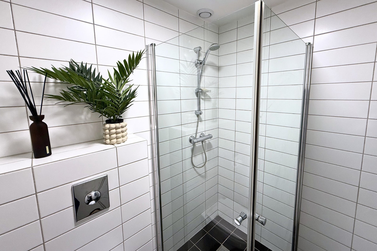 Flislagt ensuite-bad med praktisk dusjløsning og stilrene overflater. Galleribilde