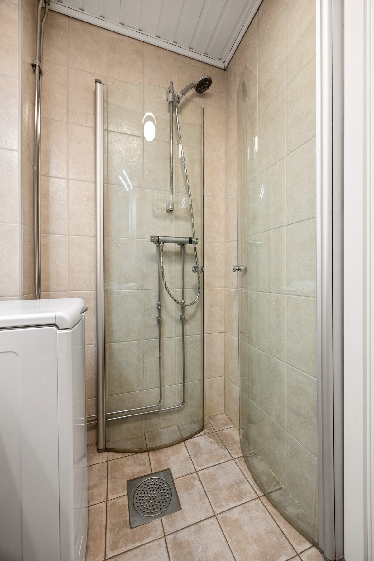 Badet er utstyrt med servantskap, toalett, dusjvegger og opplegg for vaskemaskin Galleribilde