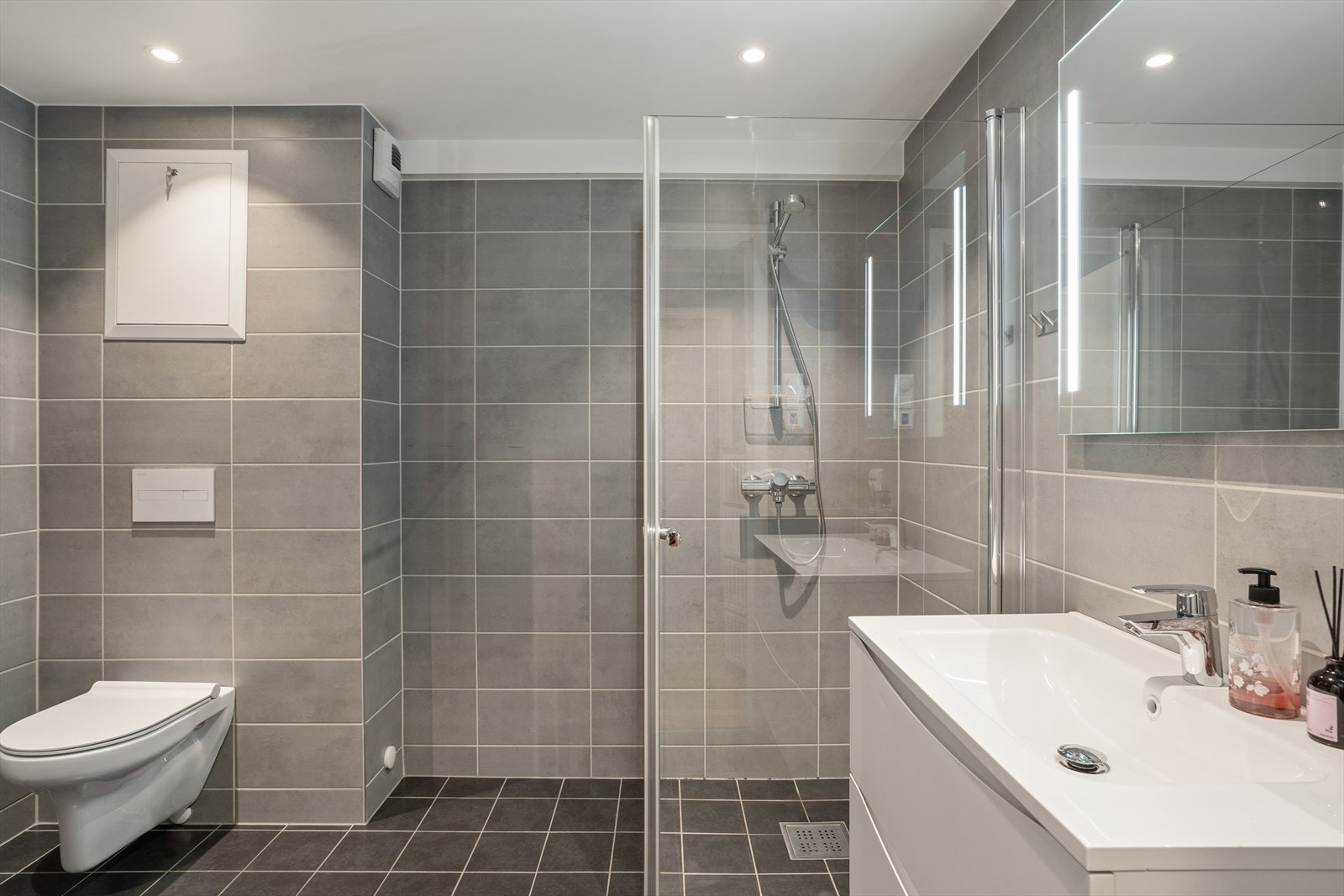 På badet er dusjhjørne, servant, vegghengt toalett og opplegg for vaskemaskin Galleribilde