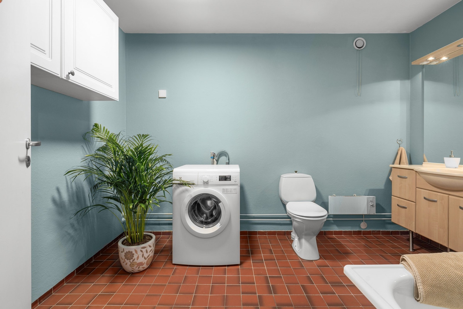 Romslig bad med flislagt gulv, badekar og opplegg for vaskemaskin. Galleribilde