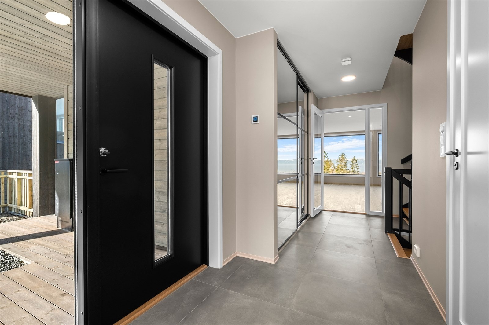 Flislagt entré/gang med 60x60 flis på gulvm med behagelig gulvvarme. Det er også en stor skyvedørsgarderobe med speil og sorte profiler samt innmat i garderobeskap Galleribilde