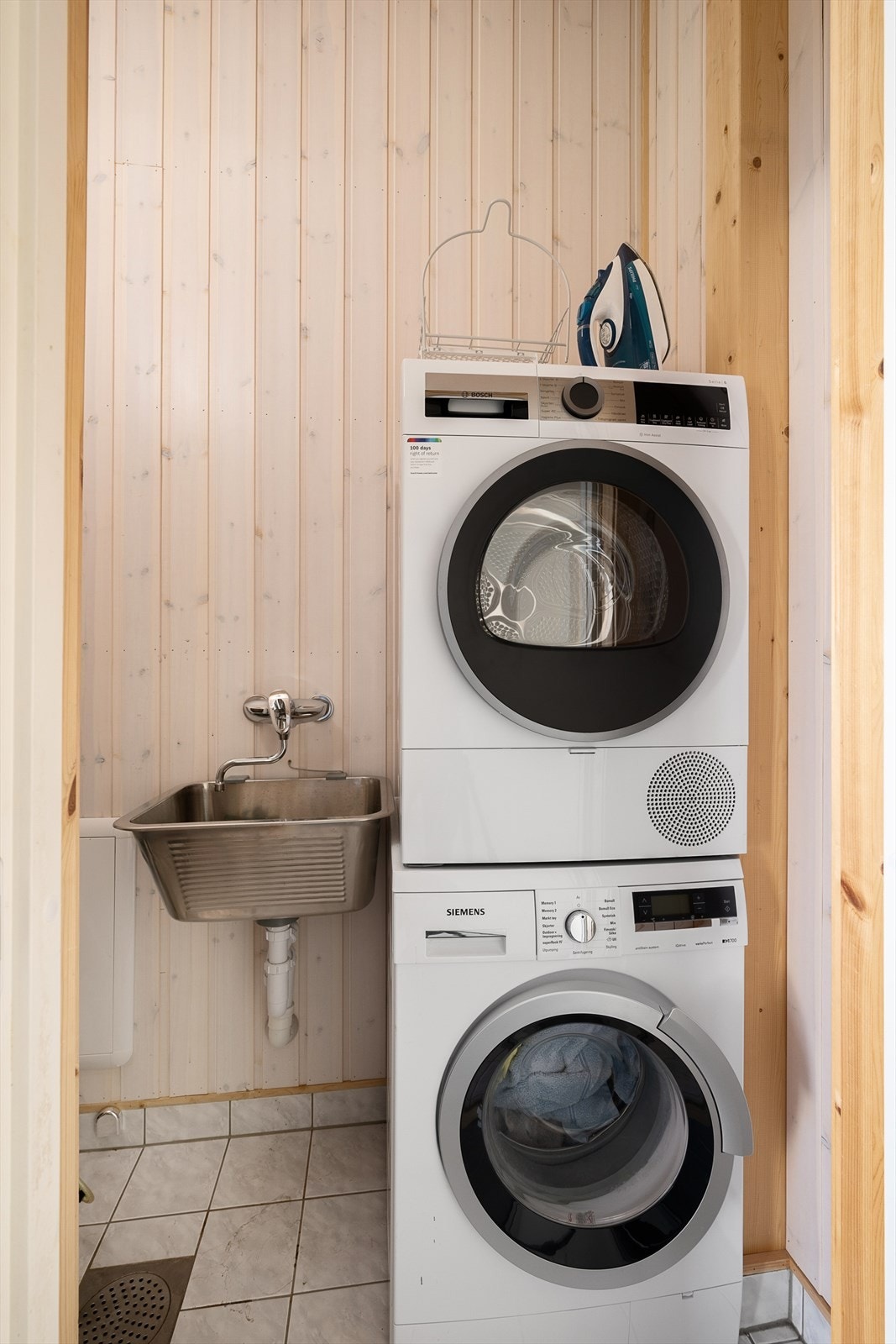 Praktisk vaskerom med flislagt gulv, gulvvarme og opplegg for vaskemaskin og tørketrommel. Galleribilde