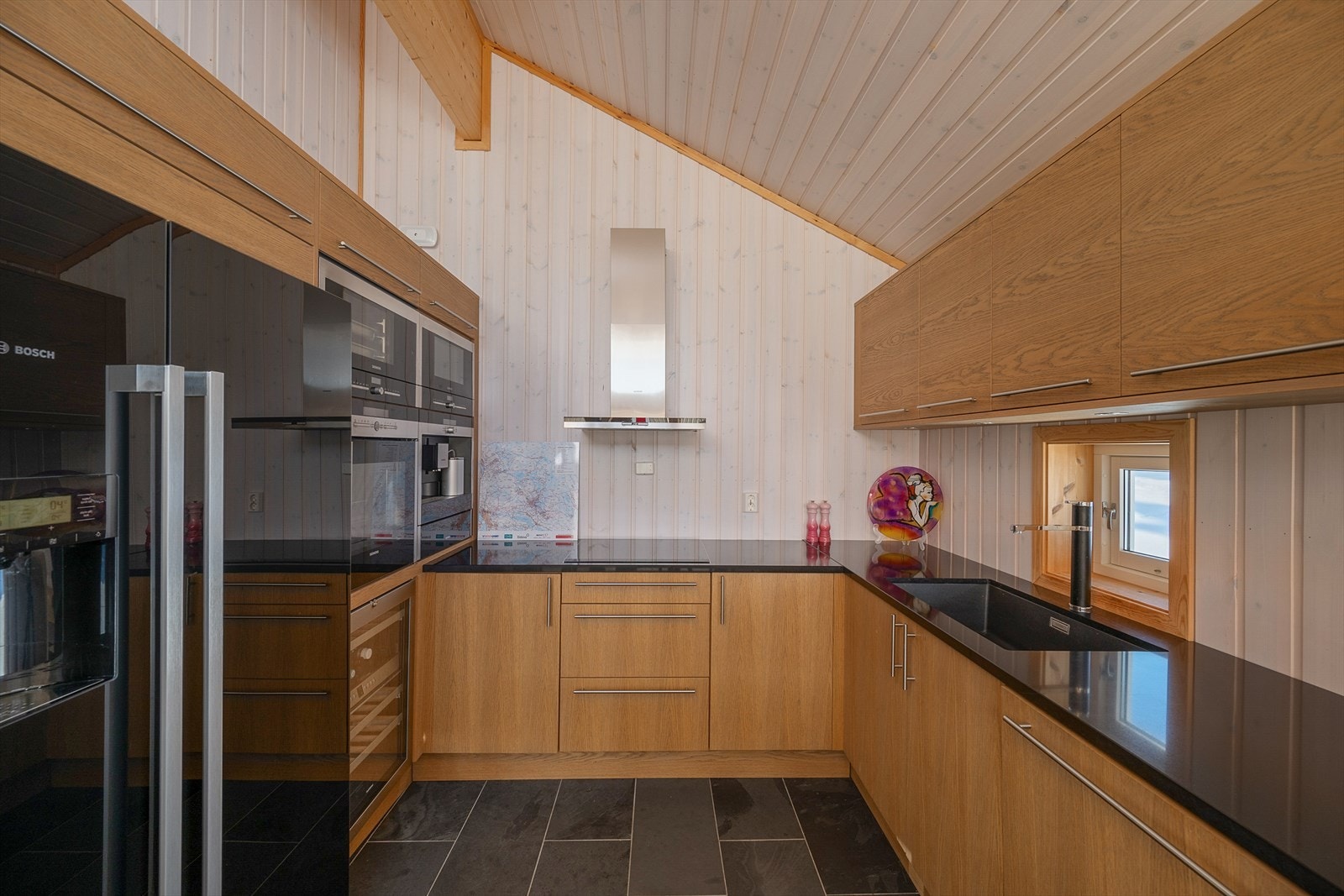 Kjøkkeninnredningen har glatte fronter og en solid benkeplate i stein. Galleribilde