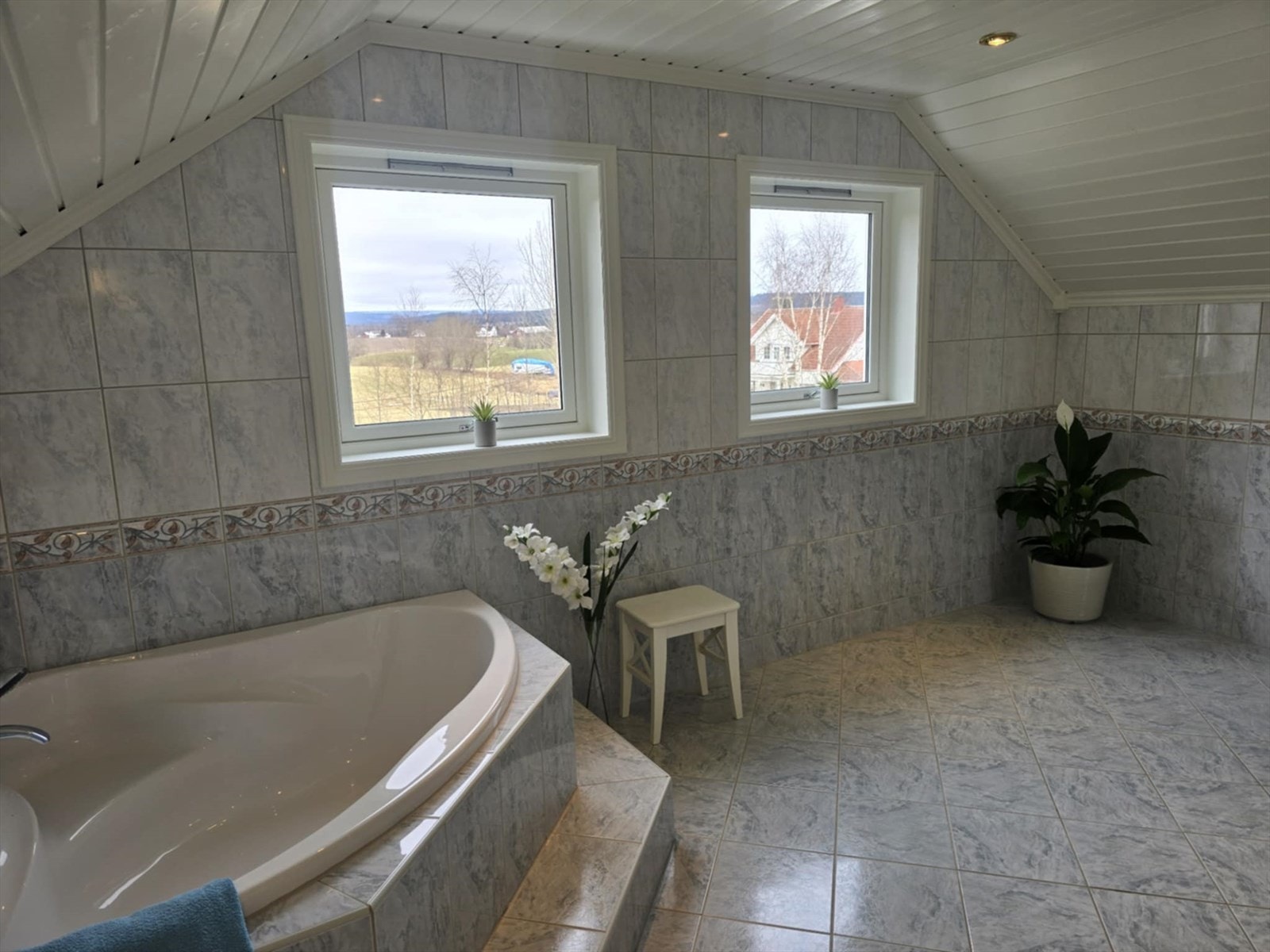 Badet er innredet med servant i baderomsinnredning, toalett og innfliset hjørnebadekar. Galleribilde