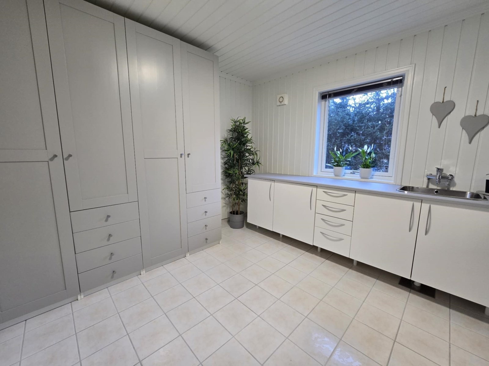 Meget praktisk vaskerom i underetasjen med gulvvarme. Innredet med skapinnredning, benk med vask og opplegg for vaskemaskin. Galleribilde