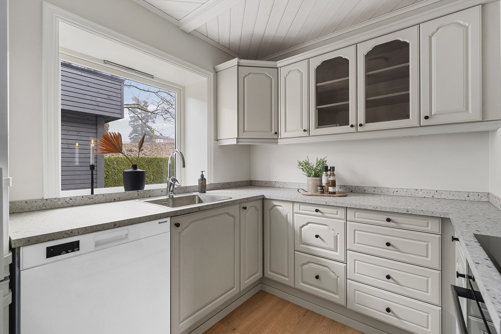 Lyst og pent kjøkken med kjøkkeninnredning type Sigdal fra 1990-tallet. Innredningen har profilerte fronter i eik, som nylig er malt. Galleribilde