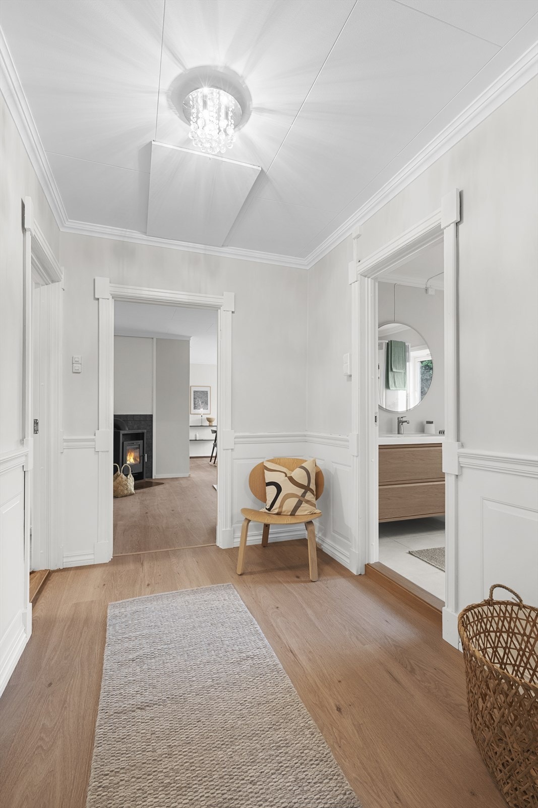 Romslig gang med lyse overflater og videre adkomst til stue, bad og soverom. Dør til trapp i malt trevirke, med nedgang til kjeller. Galleribilde