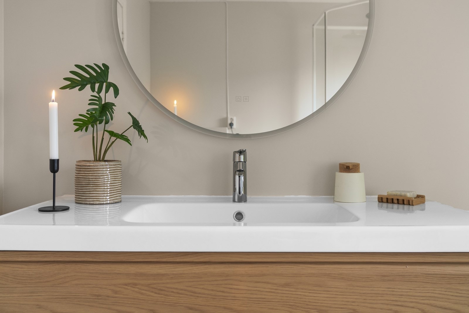 Pen og bred servantinnredning med skuffer og heldekkende servant. På vegg over servant er det montert speil med belysning. Galleribilde