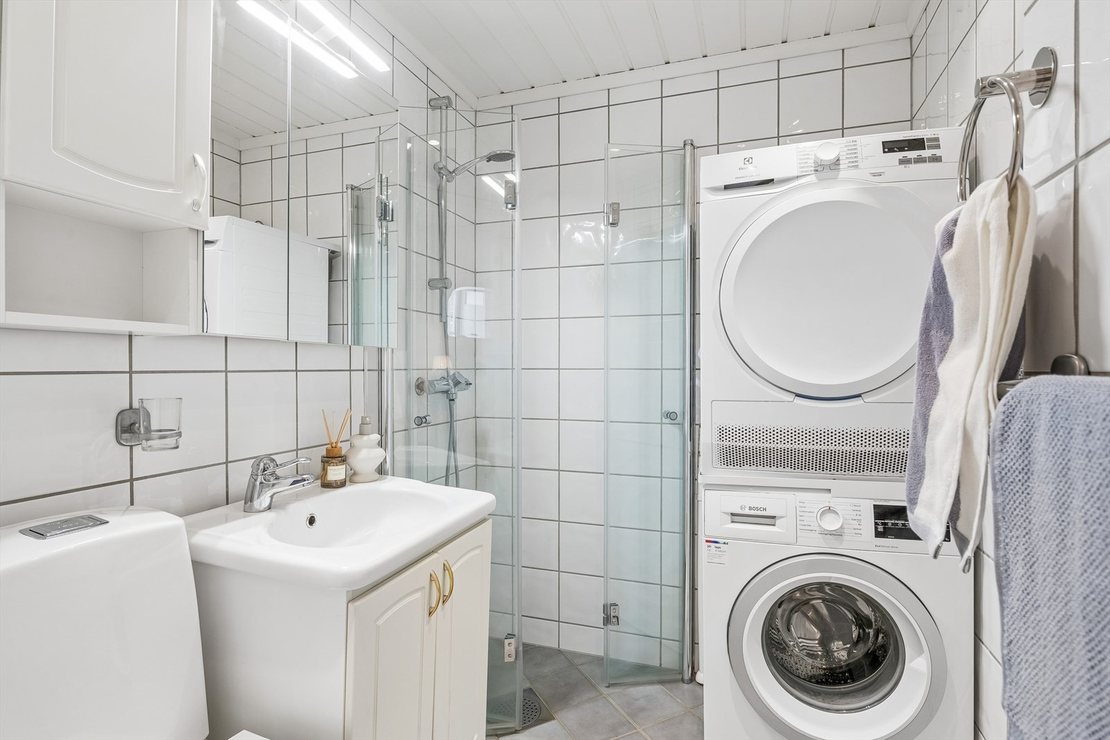 Lyst og flislagt bad med panel i taket. Galleribilde