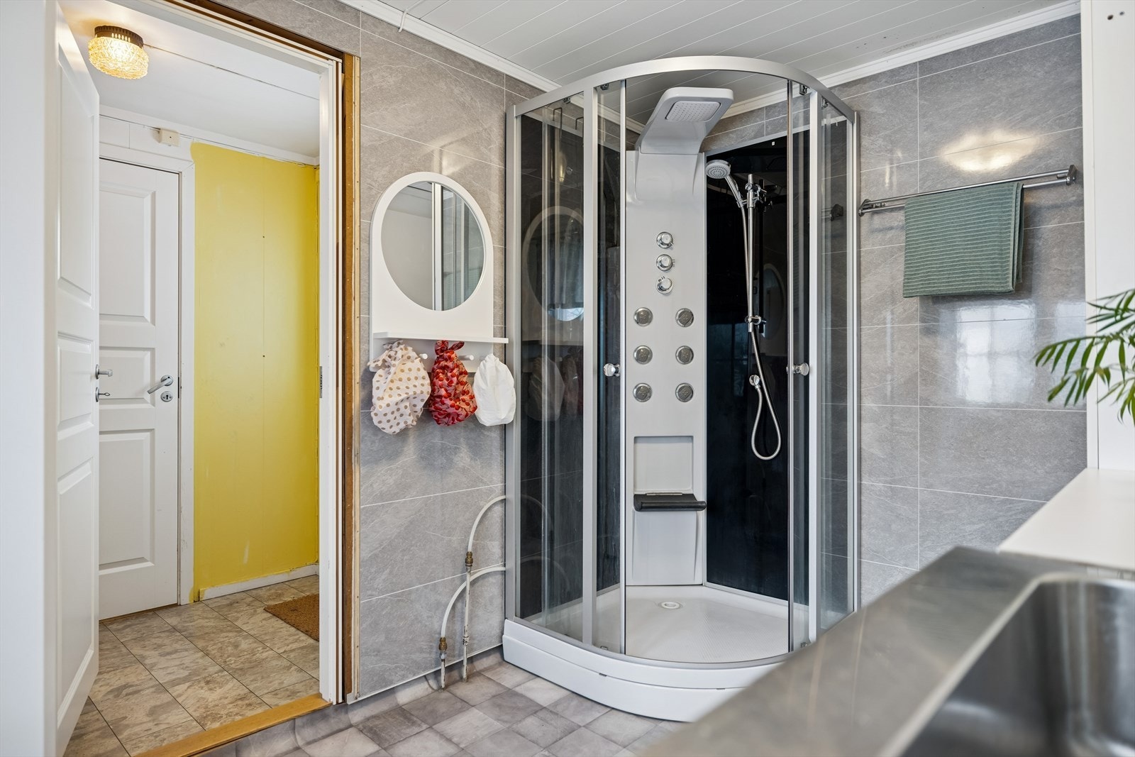 Praktisk bad/vaskerom med dusjkabinett og baderomsplater på veggene. Galleribilde