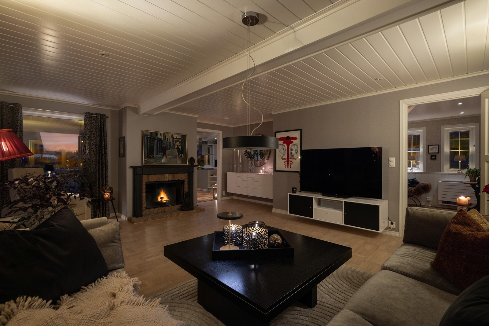 Den klassiske peisen med teglsteinsdetaljer fungerer som et naturlig og lunt midtpunkt i rommet, perfekt for kalde vinterkvelder. Galleribilde