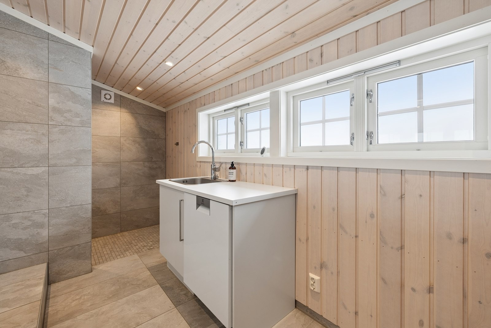 Baderommet har praktisk vask, fliser på gulv og vegger. Galleribilde