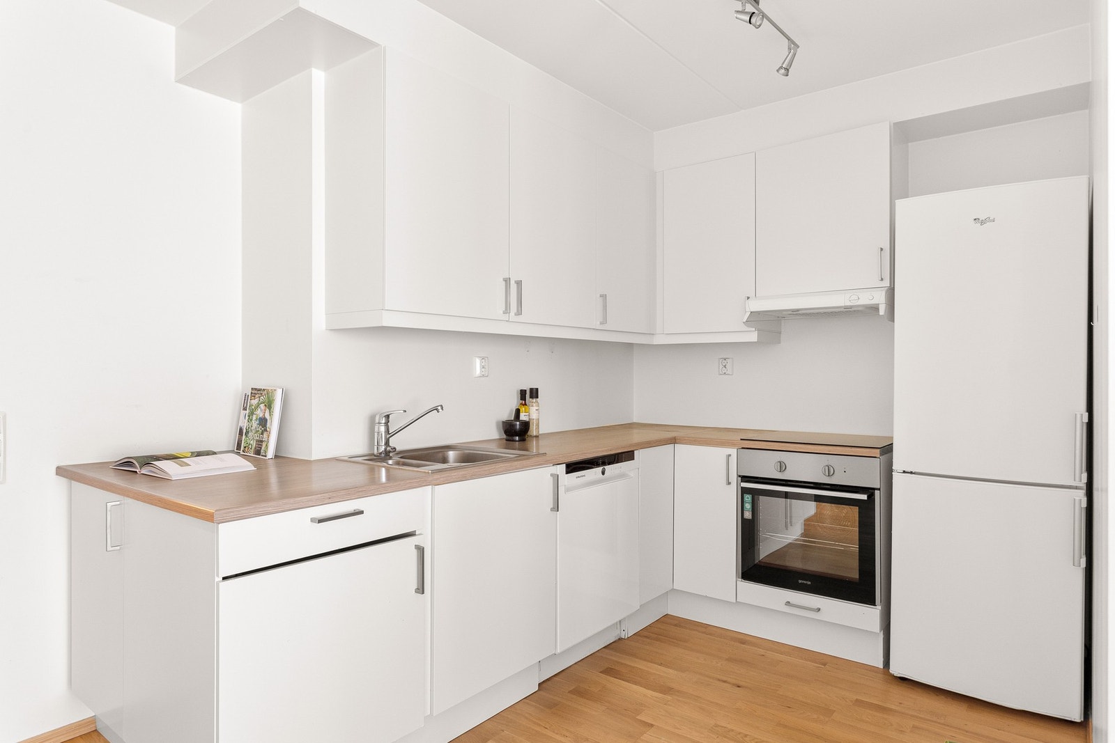 Lyst kjøkken i åpen løsning mot stuen, men likevel tilbaketrukket i hjørnet av rommet. Galleribilde