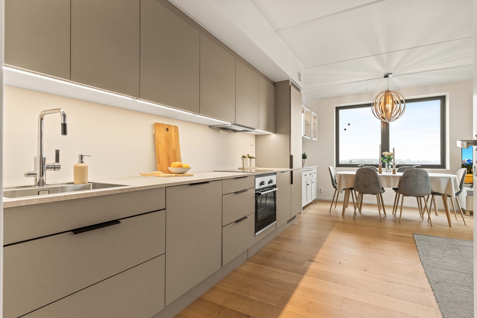 Det moderne HTH-kjøkkenet har integrerte hvitevarer og en åpen løsning mot stuen. Galleribilde