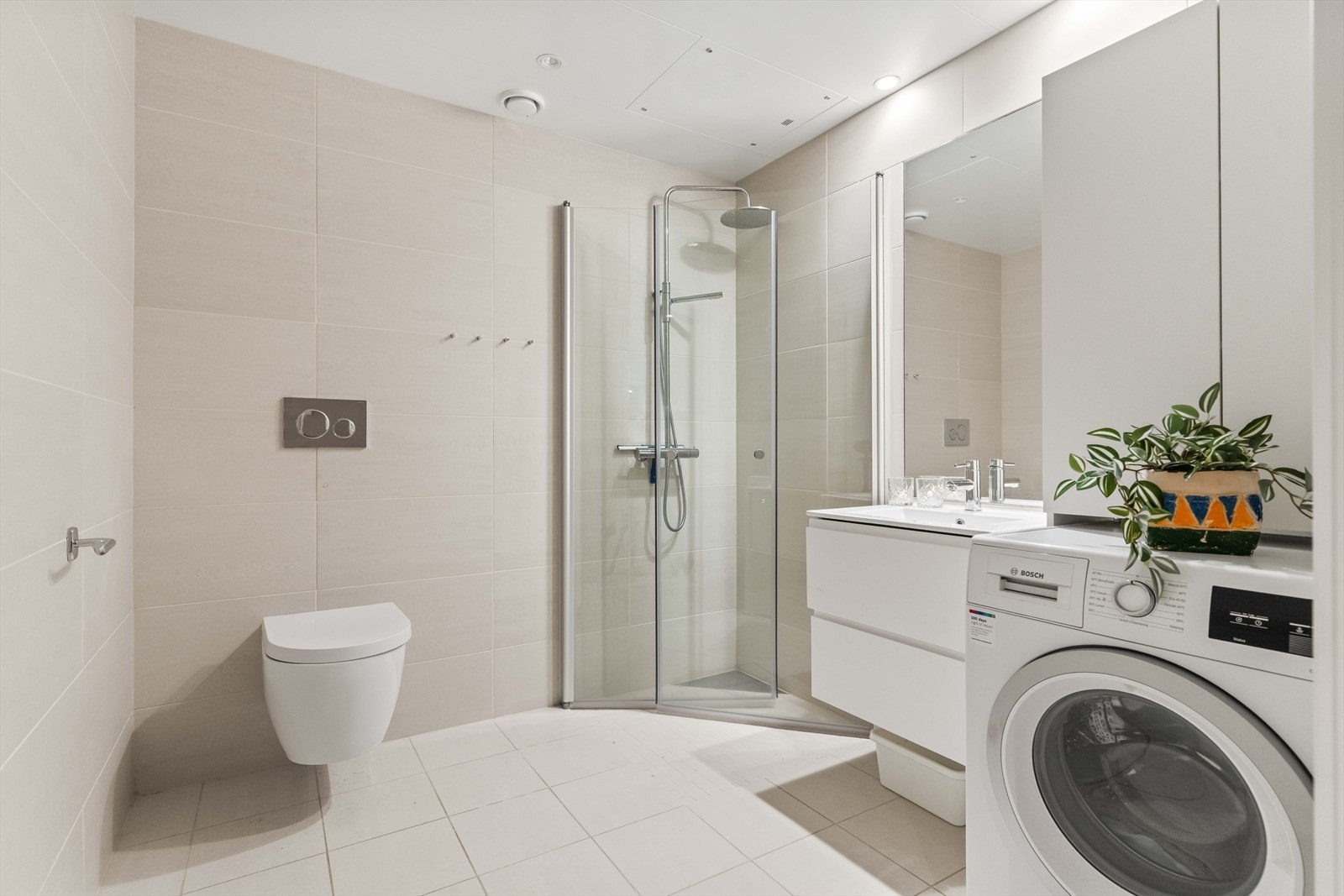 Delikat, flislagt bad fra 2023 med vannbåren gulvvarme, downlights og regnfallsdusj. Det er også opplegg for vaskemaskin. Galleribilde