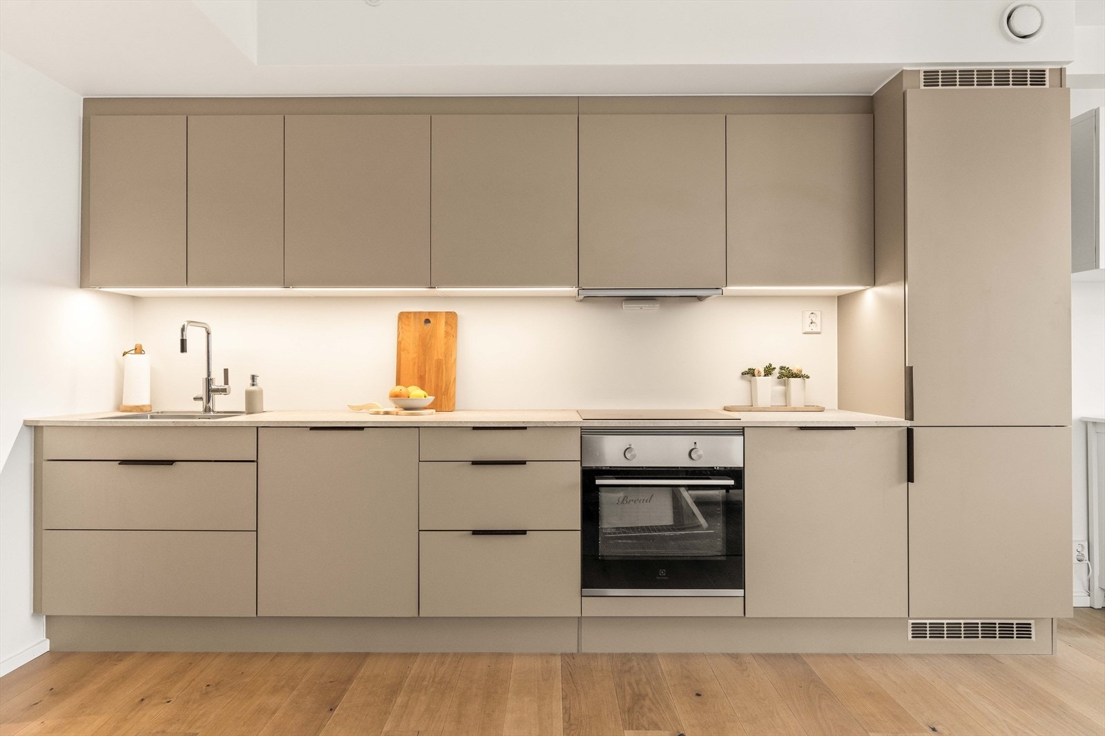 Kjøkkeninnredningen fra HTH har glatte, fabrikklakkerte fronter og laminatbenkeplate. Komfyrvakt og aquastop er installert for ekstra trygghet. Galleribilde