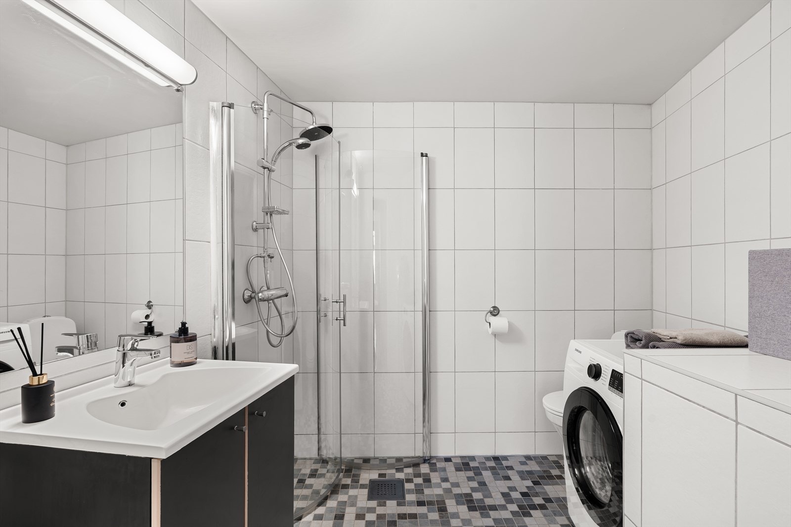 Flislagt bad med opplegg for vaskemaskin, toalett, dusjhjørne og servant med underskap. Galleribilde