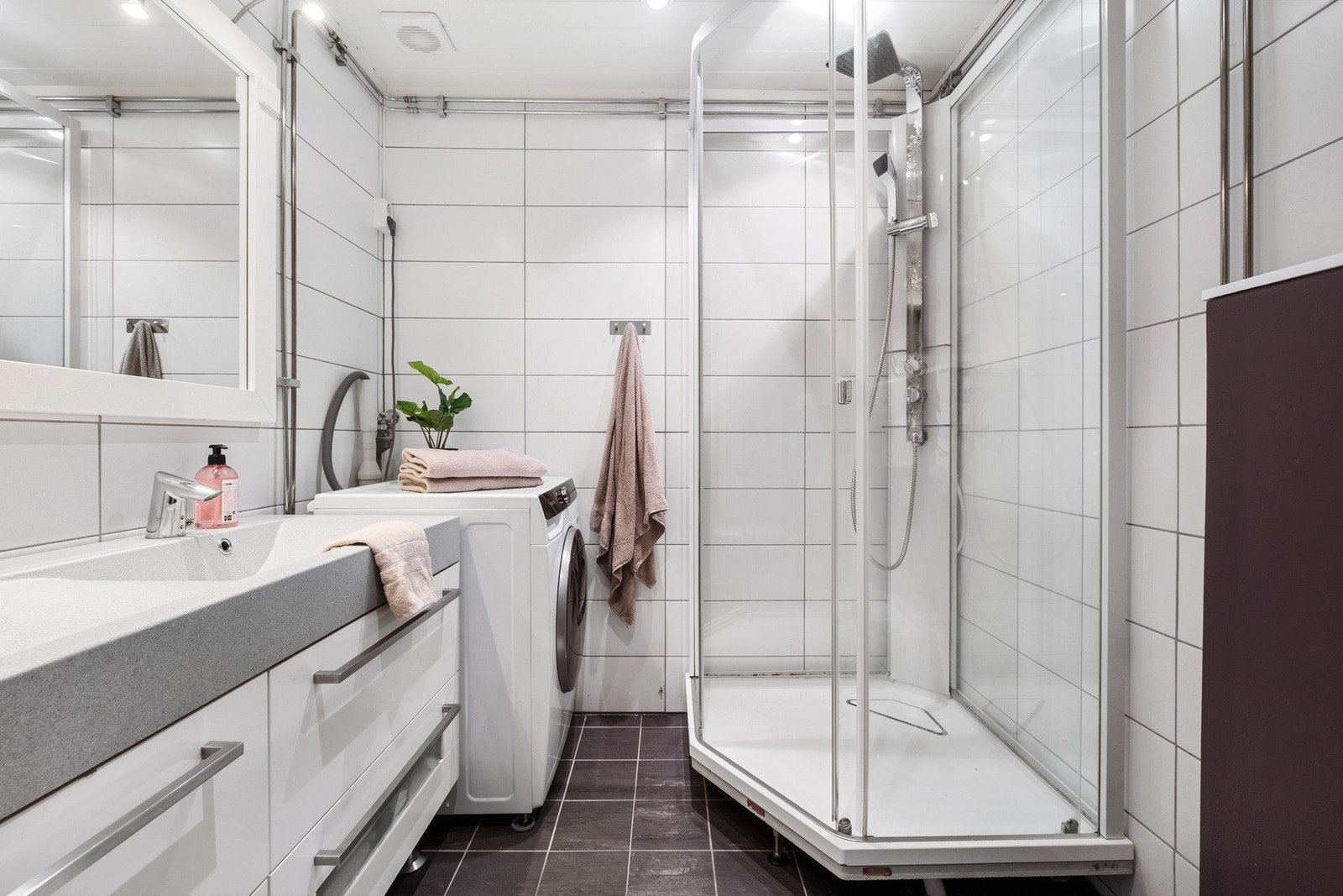 Flislagt bad med elektriske varmekabler. Innredning med to nedfelte servanter, vegghengt WC, opplegg for vaskemaskin og dusjkabinett. Galleribilde