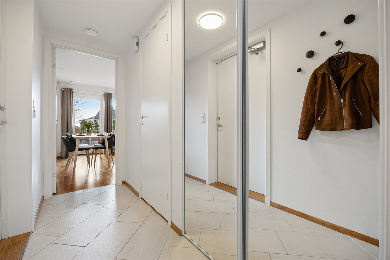 Entréen har flislagt gulv og en praktisk skyvedørsgarderobe med speilfronter for god oppbevaring. Galleribilde