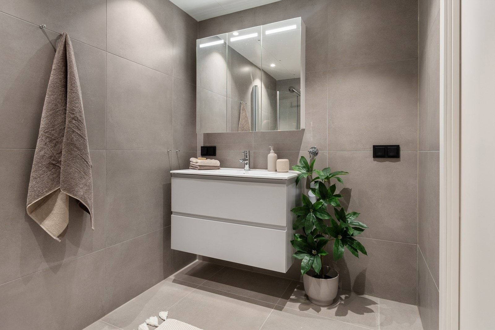 Badet er utstyrt med vegghengt toalett, hjørnedusj med innfellbare dusjdører og opplegg for vaskemaskin. Galleribilde