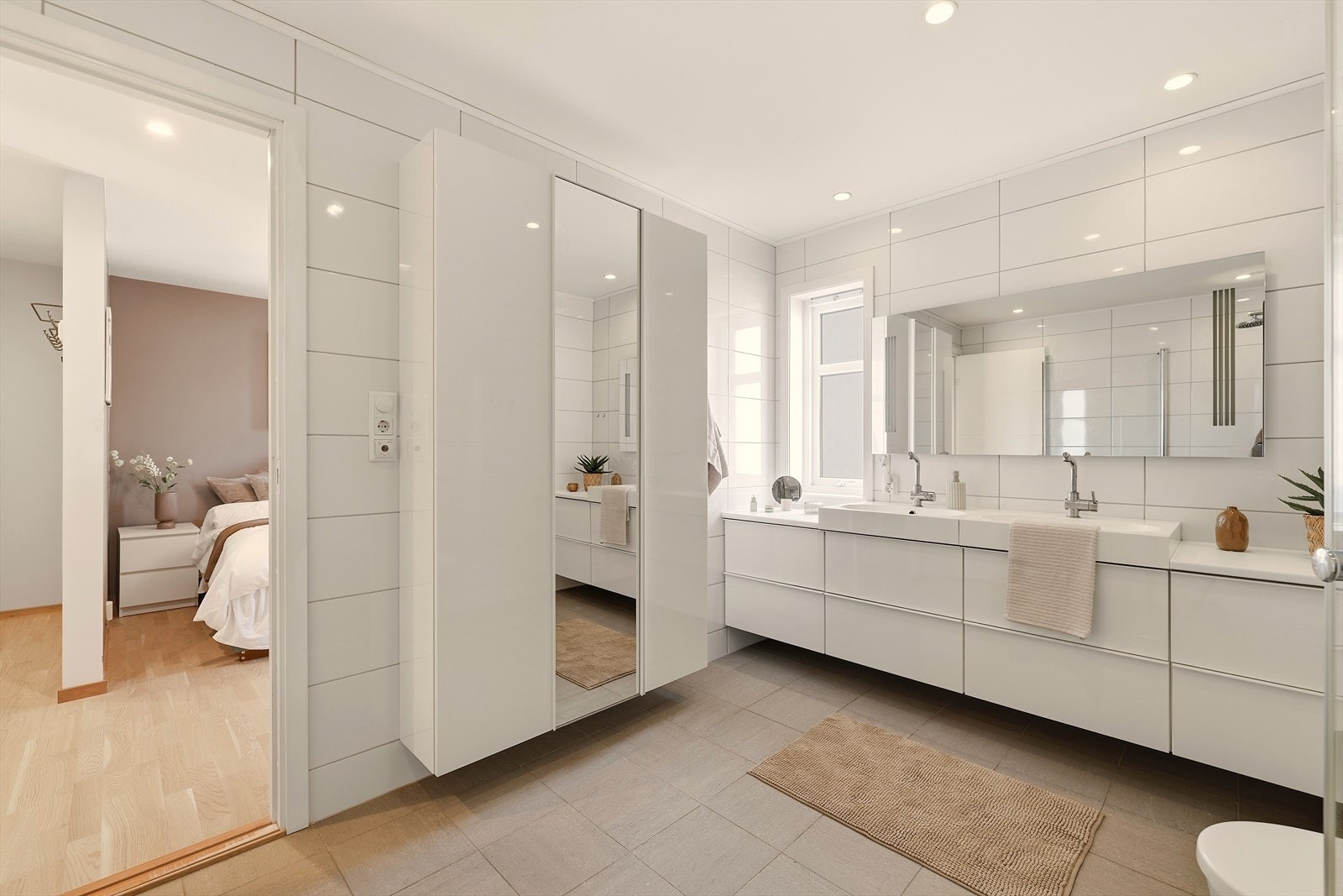 Dette badet inneholder baderomsmøbel med slette fronter, benkeplate i laminat og to porselensvasker med ett-greps blandebatterier, speil med integrert belysning, veggskap,
vegghengt toalett og dusj med innfellbare dører i herdet glass. Galleribilde