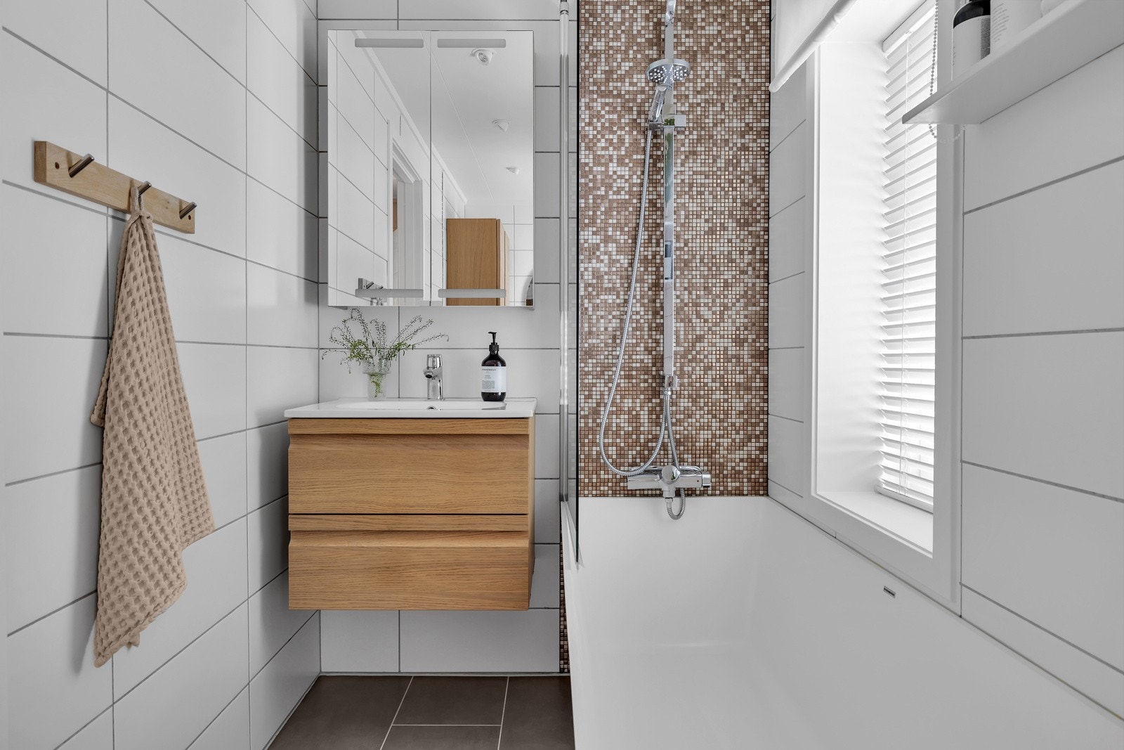 Badet er pent flislagt på gulv og vegger. Moderne innredning og badekar Galleribilde