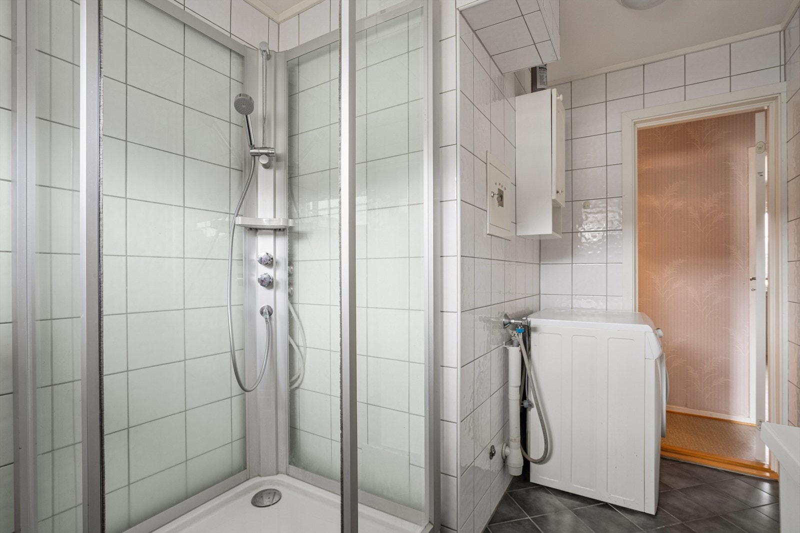 Badet er utstyrt med dusjkabinett, lys baderomsinnredning og opplegg for vaskemaskin. Galleribilde