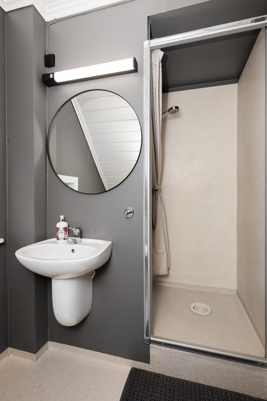 Her er det gulvmontert toalett, vegghengt servant og forhøyet dusjnisje med forheng. Over servant er det montert speil og overlys. Galleribilde