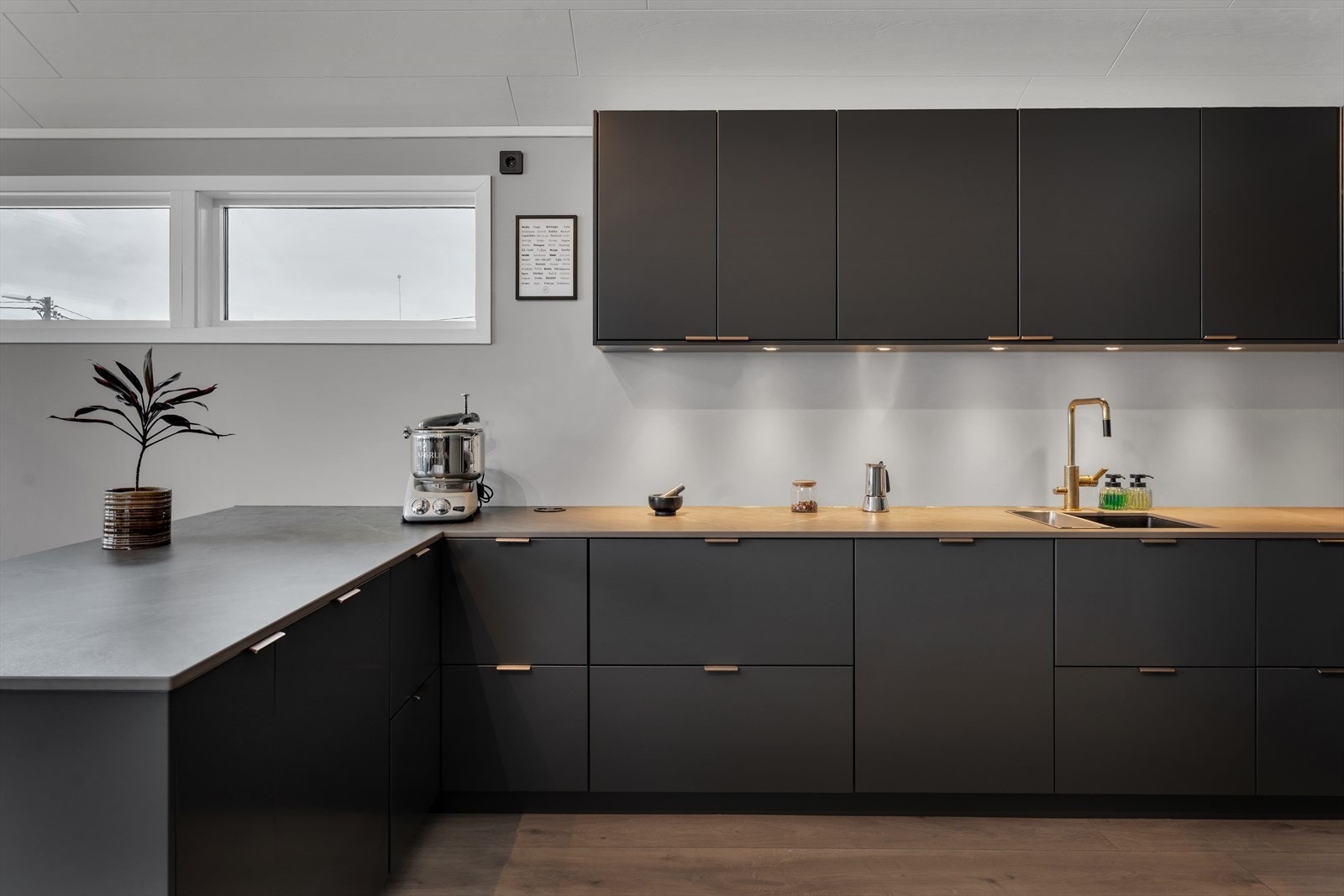 Innbydende kjøkken i mørk utførelse med integrerte hvitevarer og moderne innredninger. Galleribilde