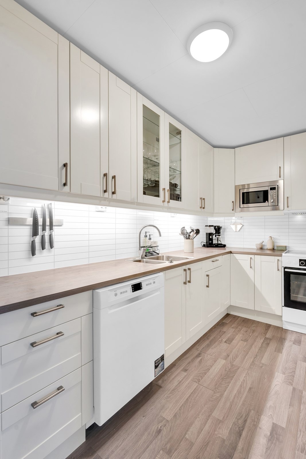 Flott kjøkken i hvit utførelse med profilerte fronter og delvis integrerte hvitevarer. Galleribilde