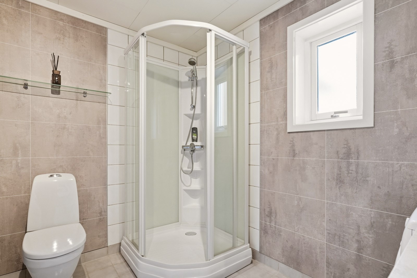 Gulvet er flislagt med varmekabler. Veggene er kledd med baderomspanel og fliser. Galleribilde