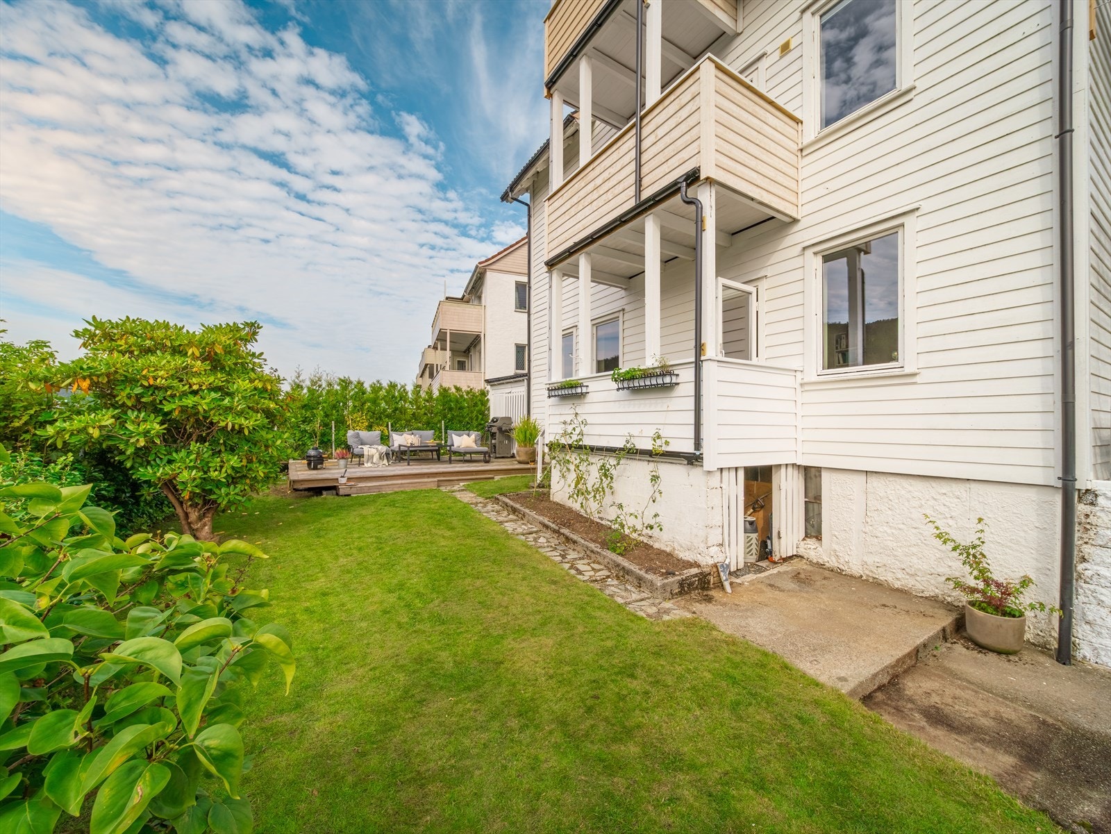 Bed med diverse sesongbaserte løker, stauder, ramsløk og blomstrende rosebed i bakkant av terrassen. Galleribilde