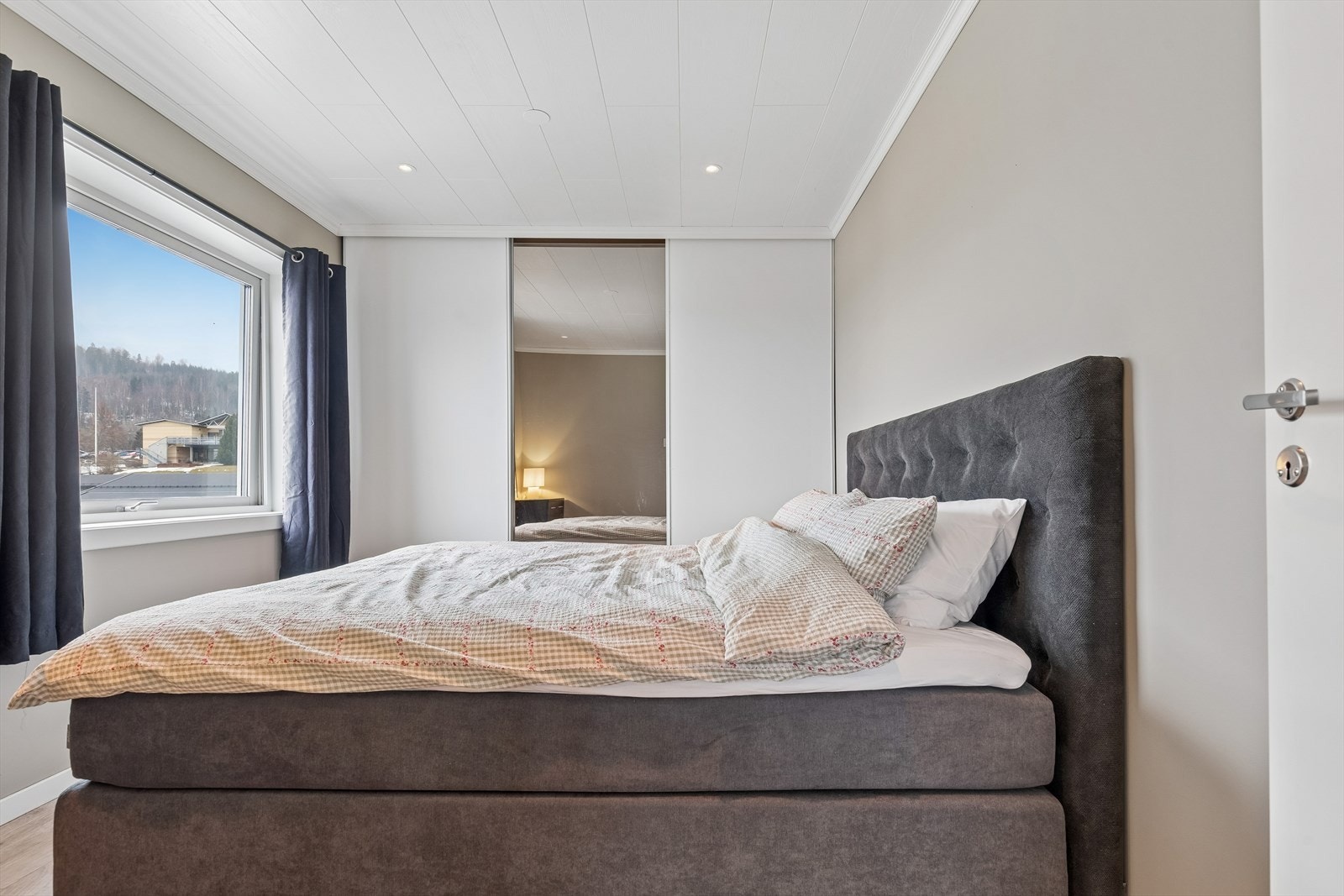 En romslig skyvedørsgarderobe med speilfronter gir rikelig med oppbevaringsplass. Galleribilde