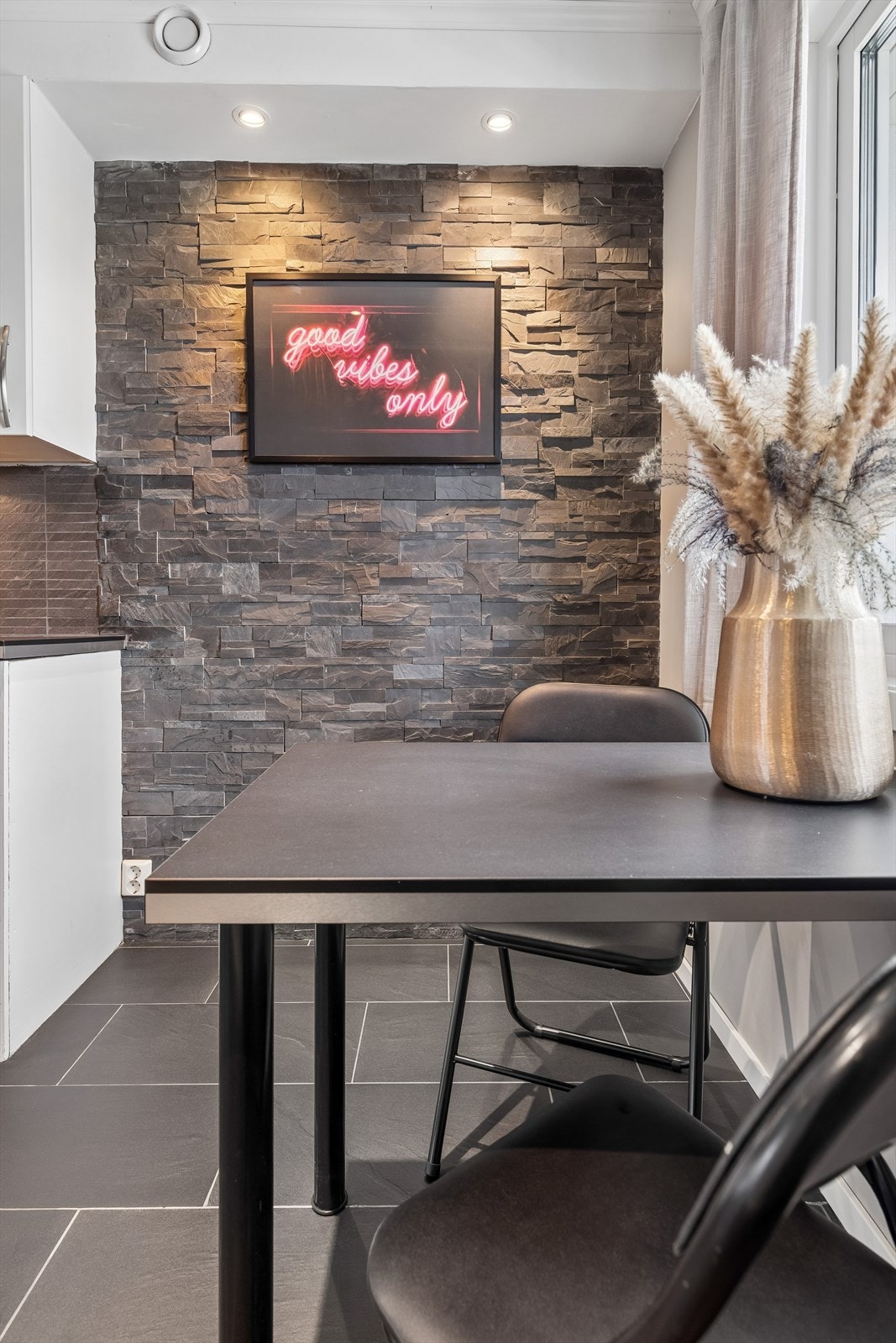 En dekorvegg med steinfliser og downlights skaper en stilig sone for en liten spiseplass. Galleribilde