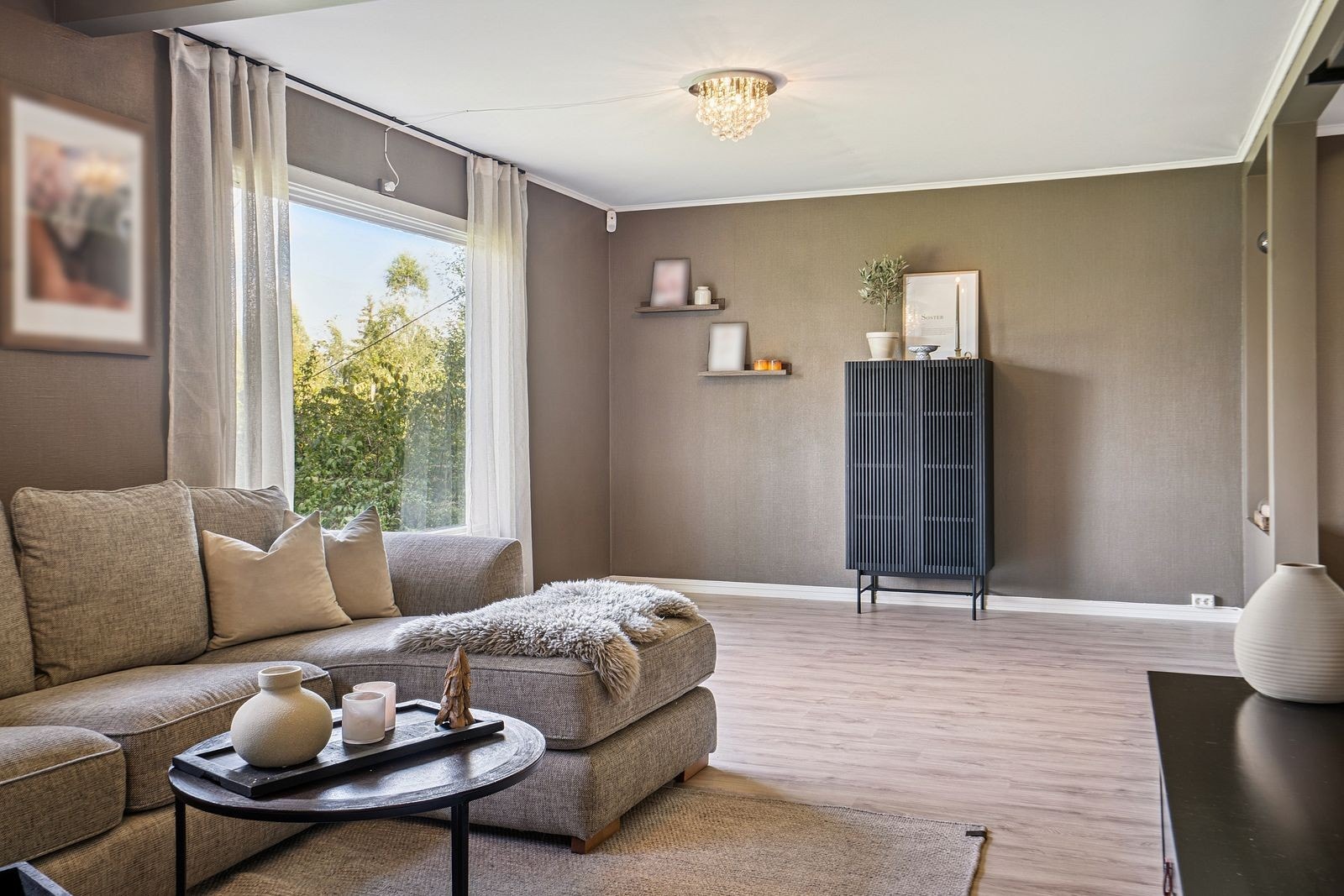 Stuen har malte vegger i en varm fargetone, laminatgulv og store vindusflater som gir et godt lys inn. Galleribilde