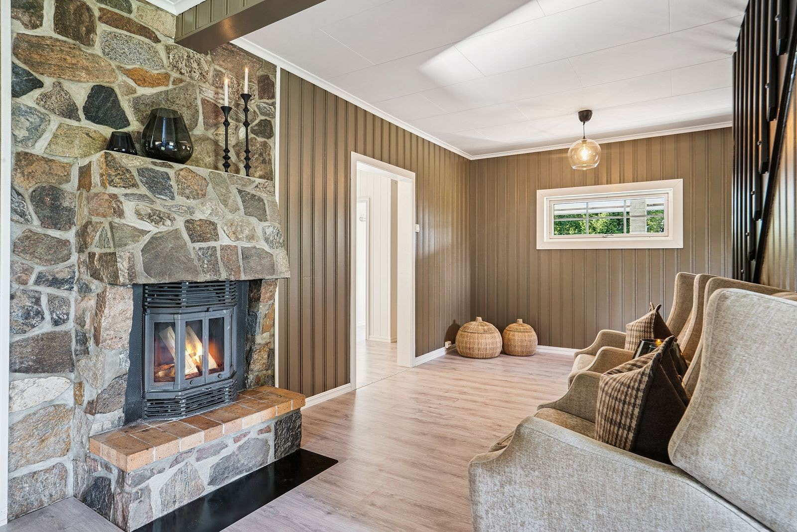 Den gode varmen i stuen får man fra denne fine peisovnen - Pipeveggen er pent kledd med kleberstein. Galleribilde