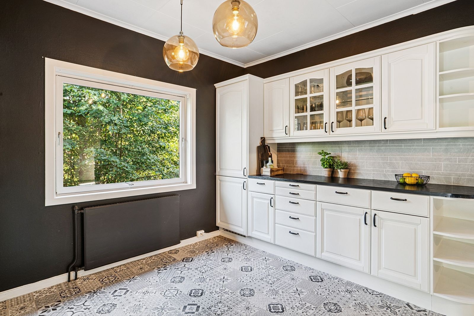 Kjøkkenet har malte vegger i en mørk nyanse og flismønstret gulvbelegg. Galleribilde