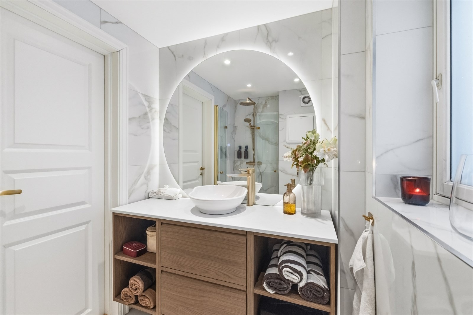 Innredning med heldekkende benkeplate og toppmontert servant, kombinert med underskap og speil med lysarmatur på vegg. Galleribilde