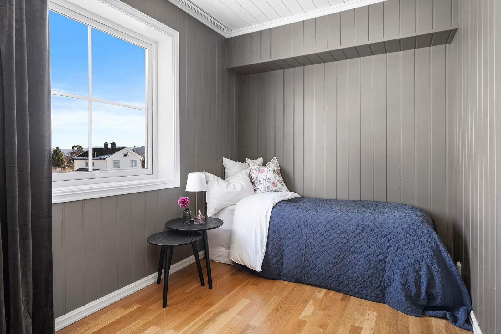 Praktisk og lunt soverom med dempede farger og et stort vindu som slipper inn rikelig med naturlig lys. Galleribilde