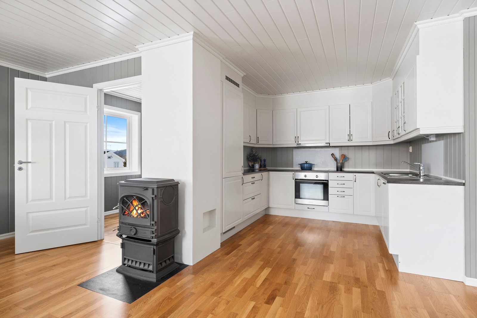 Koselig peis plassert sentralt mellom stue og kjøkken, som skaper en lun og varm atmosfære i rommet. Galleribilde