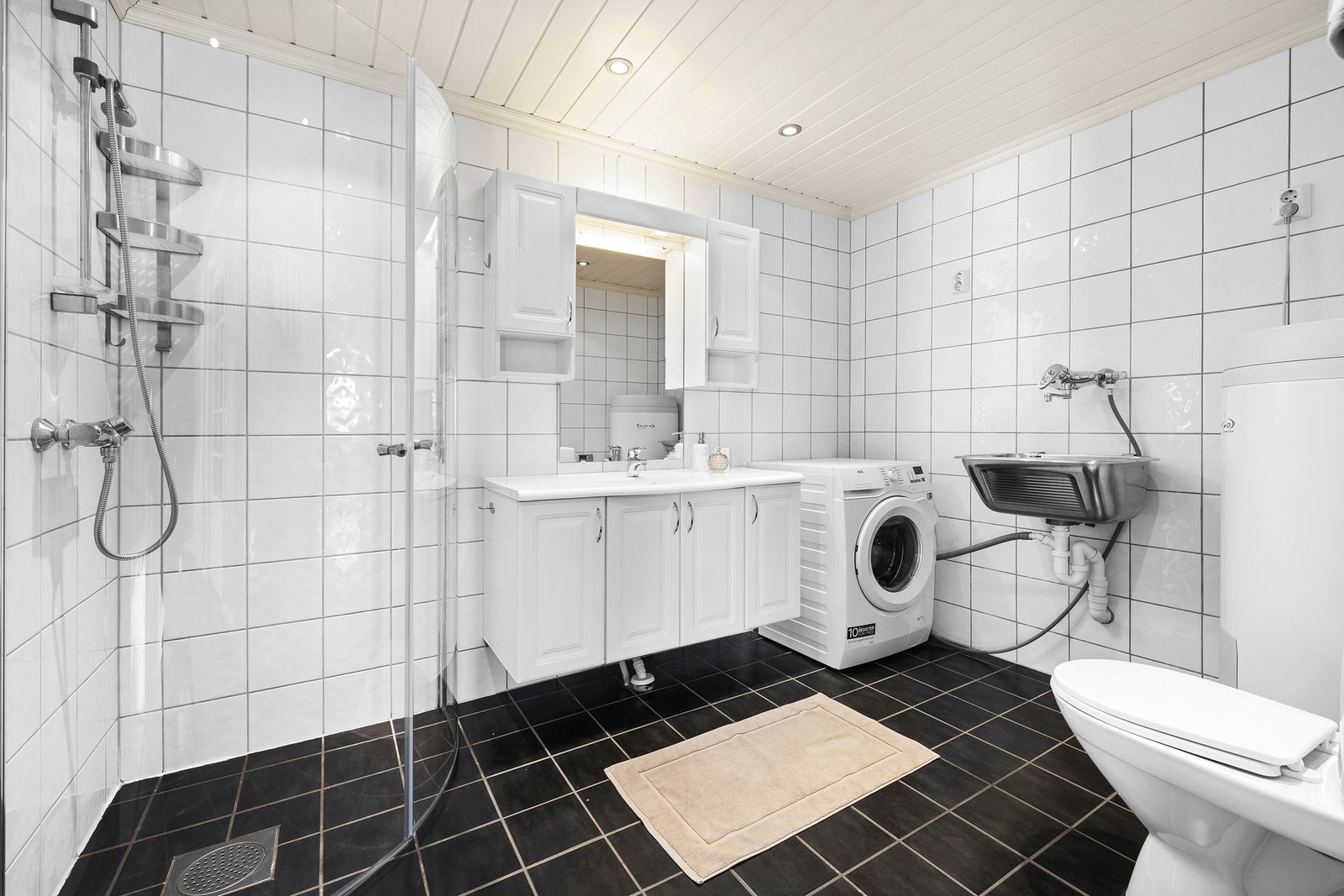 Badet inneholder dusj, servant med innredning, toalett, vaskemaskin, praktisk skyllekum og varmtvannsbereder. Galleribilde