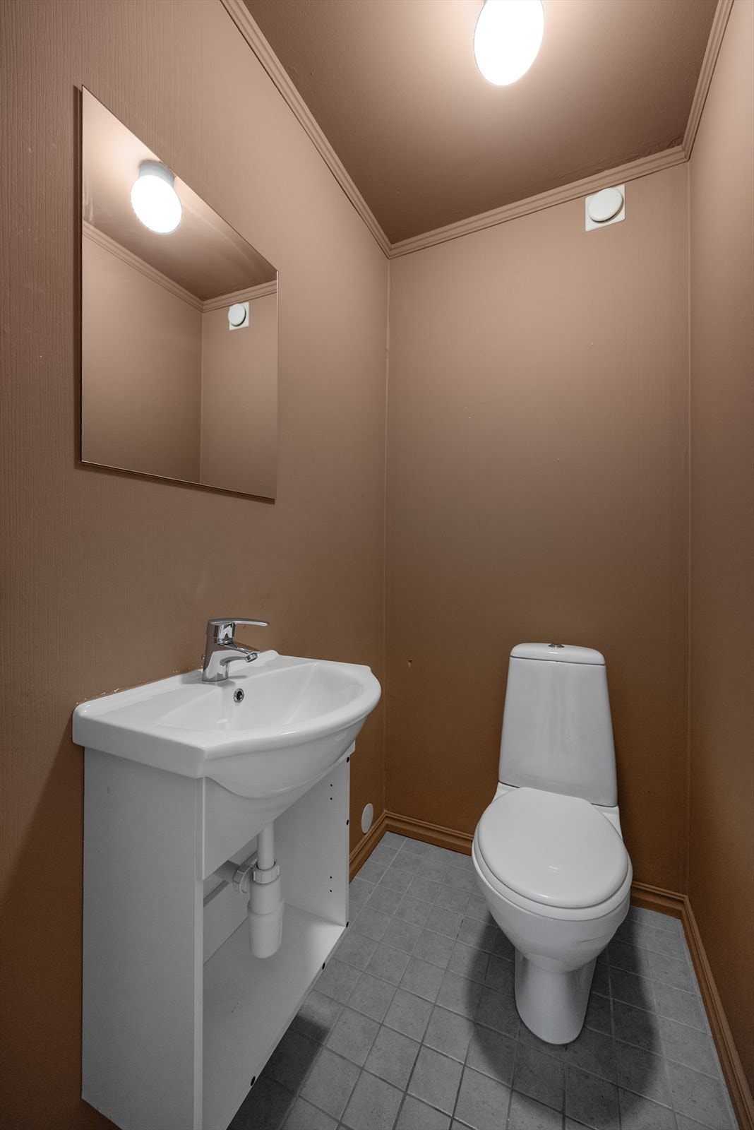 Inntil badet er det eget toalettrom med flislagt gulv og malte veggoverflater. Toalettrommet har vaskeservant og toalett. Innredning mangler fronter. Galleribilde