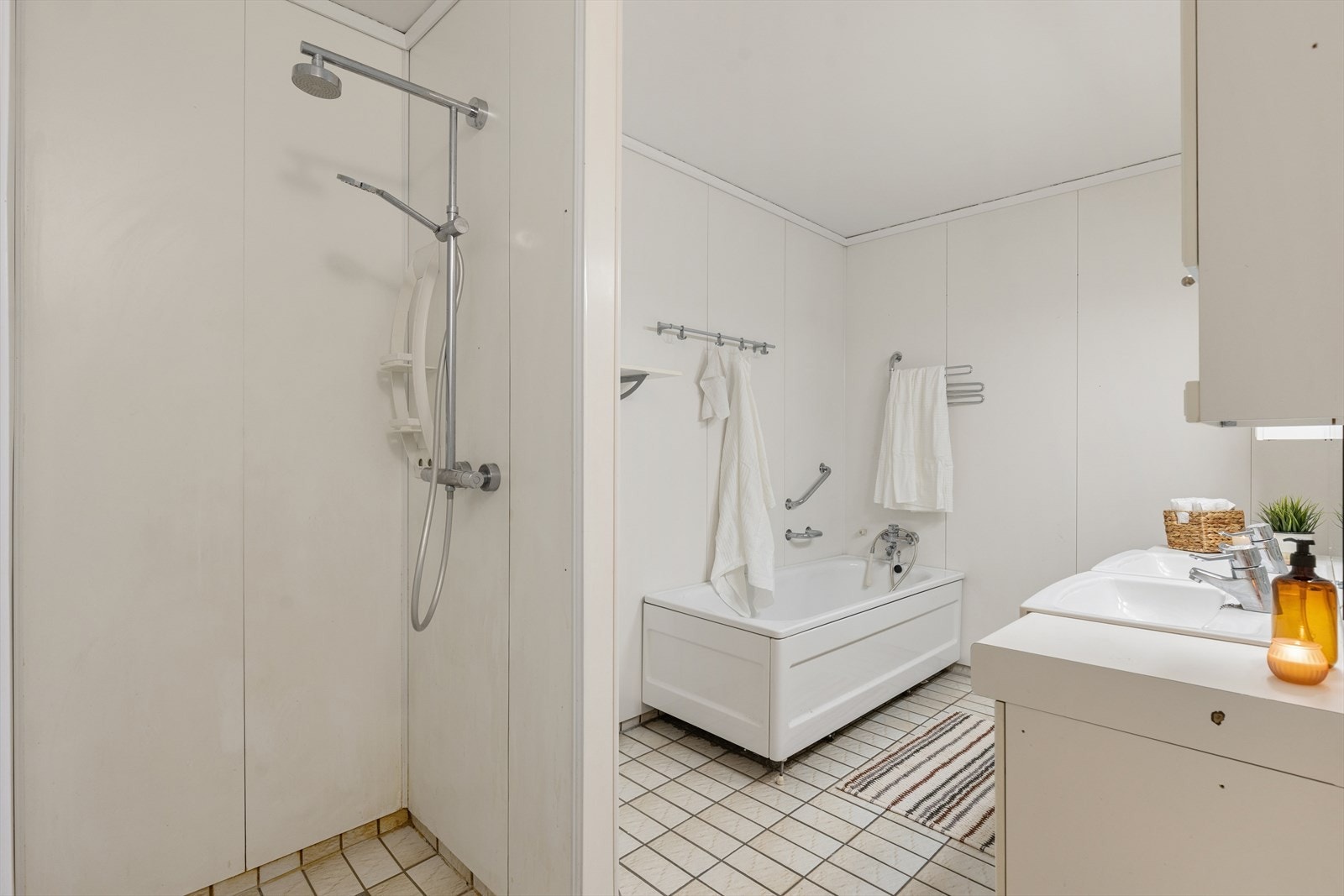 Flisbelagt baderom med badekar, dusj på vegg og elektrisk gulvvarme. Galleribilde